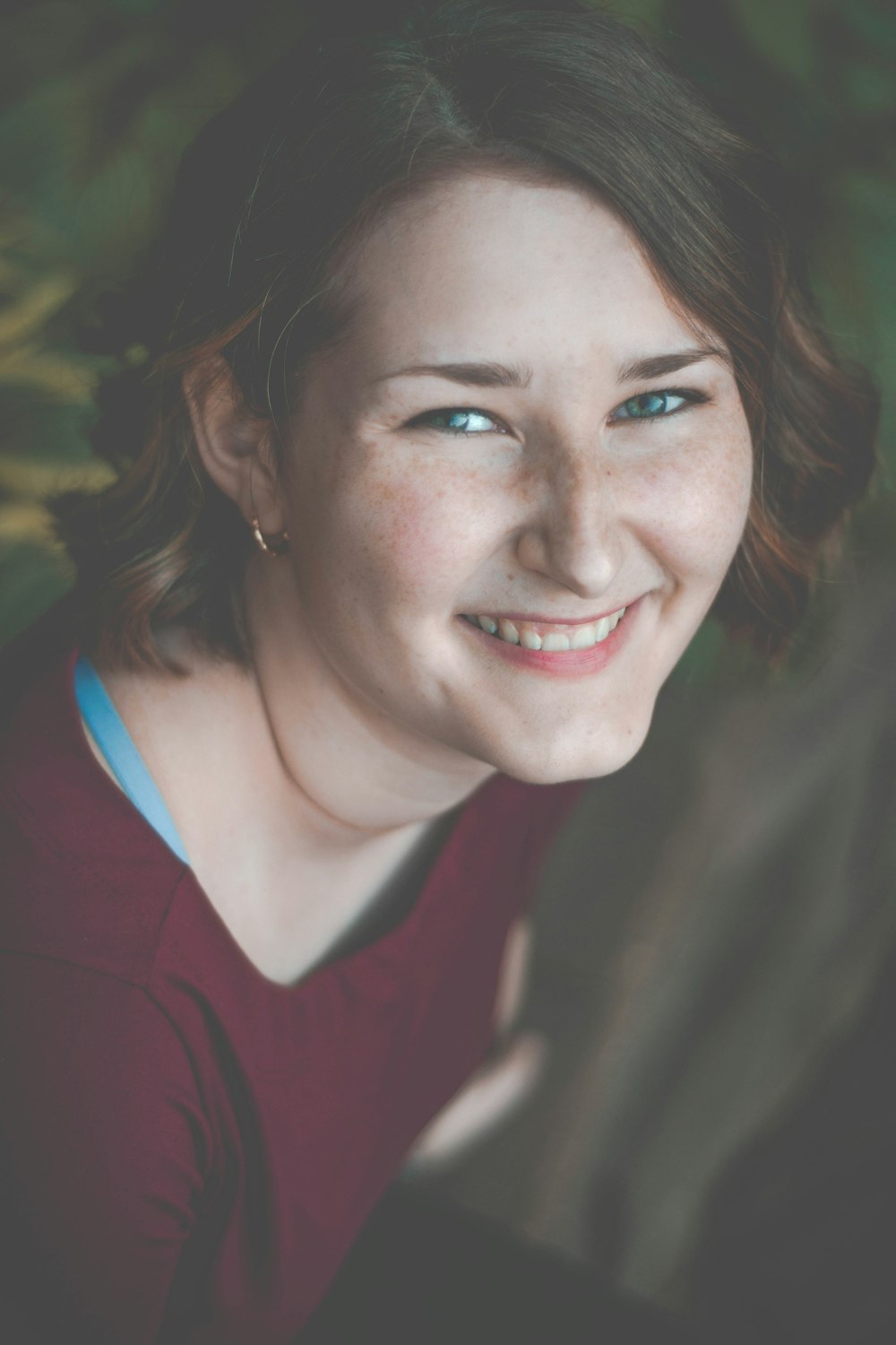 woman smiles and sits near plants