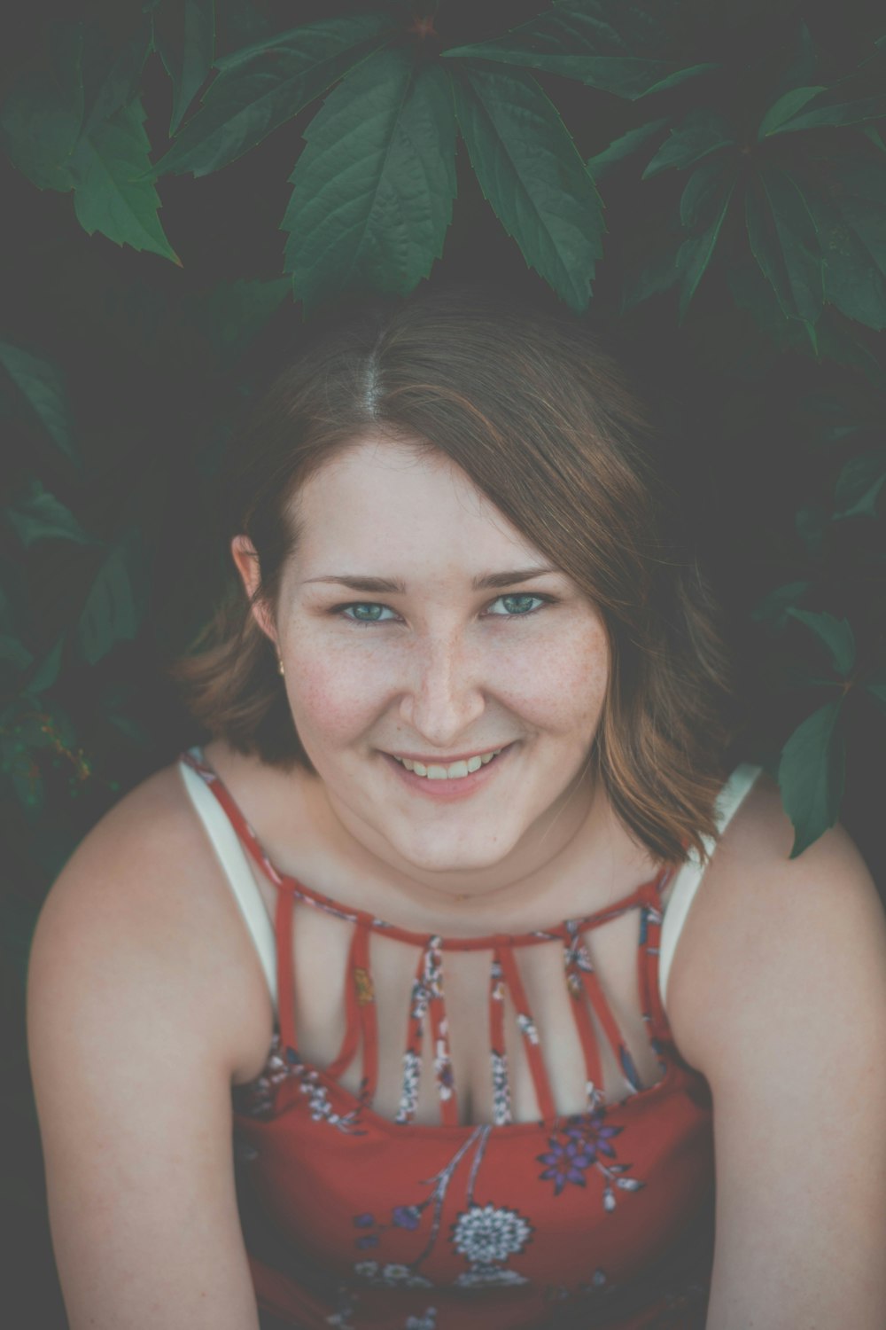 woman smiling while standing near green leaf plant