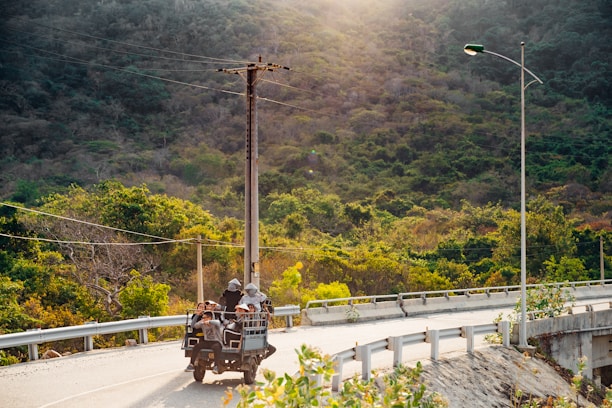 A group of tourists riding quadricycles on a rugged mountain trail in Monte Verde with lush greenery around.