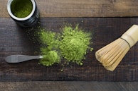 A close-up of matcha powder in a small bowl with a bamboo whisk.