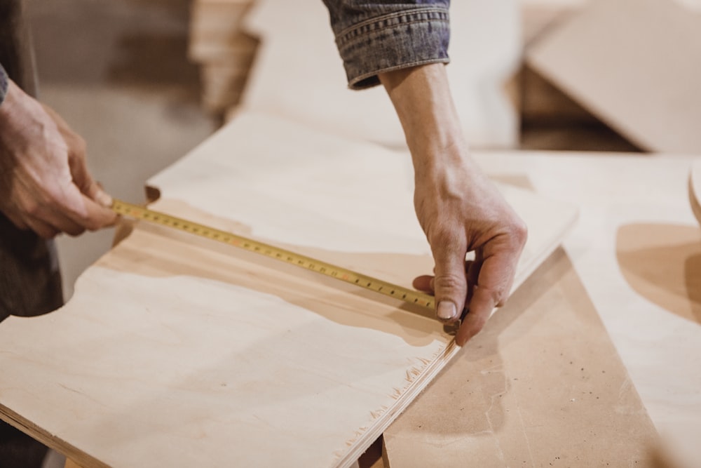 person measuring brown board