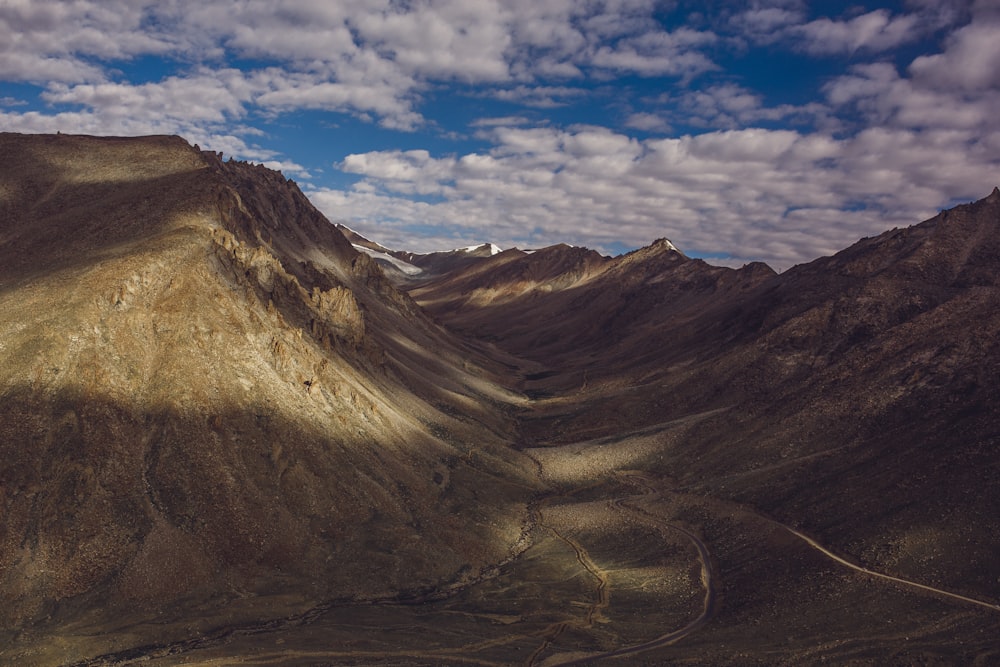 brown-and-green mountains under white clouds and blue sky