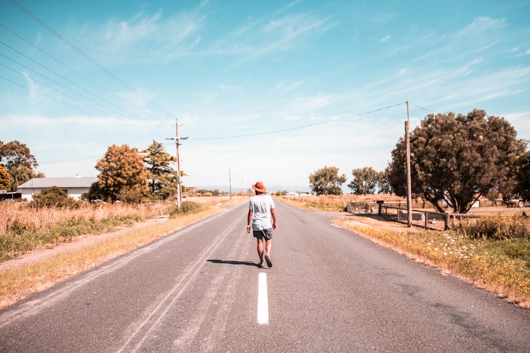 person walking on a road under blue sky during daytime