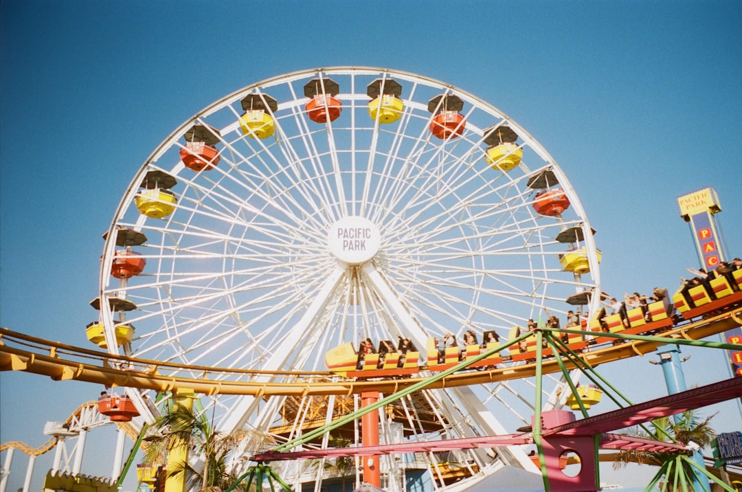 white fairy's wheel near roller coaster under blue sky during daytime