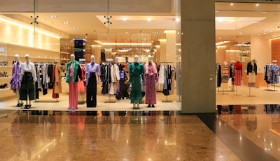 A selection of stylish fashion apparel displayed on mannequins with bright lighting.