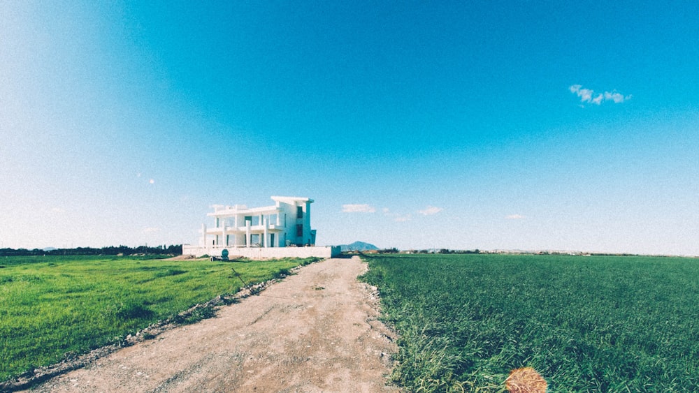 white concrete house surrounded by grass field under clear sky