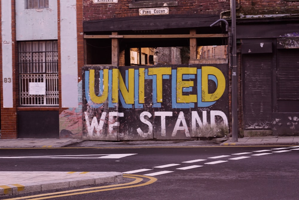 united we stand paint written on the wall near sidewalk