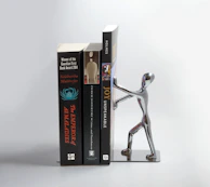 A sleek metal bookend set holding a collection of well-loved books on a minimalist desk.