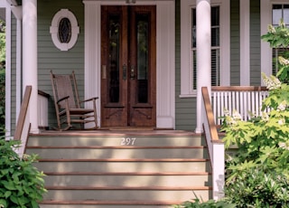 brown wooden rocking chair on porch beside closed French doors