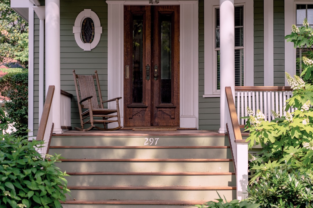 brown wooden rocking chair on porch beside closed French doors,