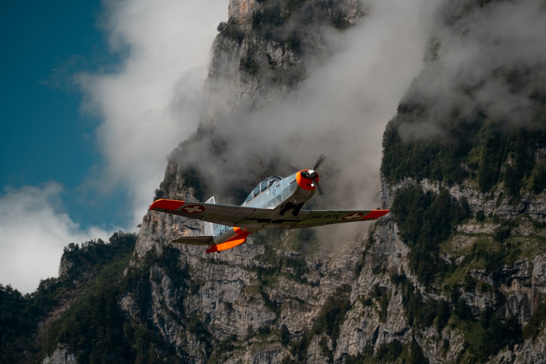 gray and orange single-propeller plane near gray mountain