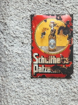 A rustic tin wall sign with a custom logo hanging on a textured brick wall, highlighting its vintage appeal.