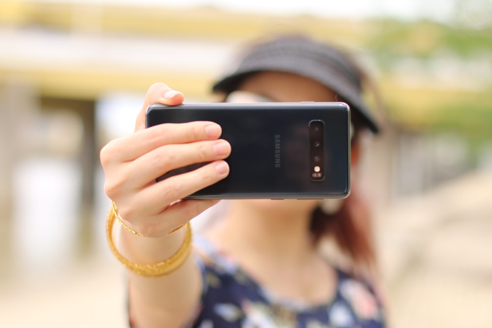 mujer mostrando un teléfono inteligente Samsung negro