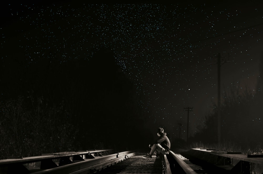 person sitting on railroad at night