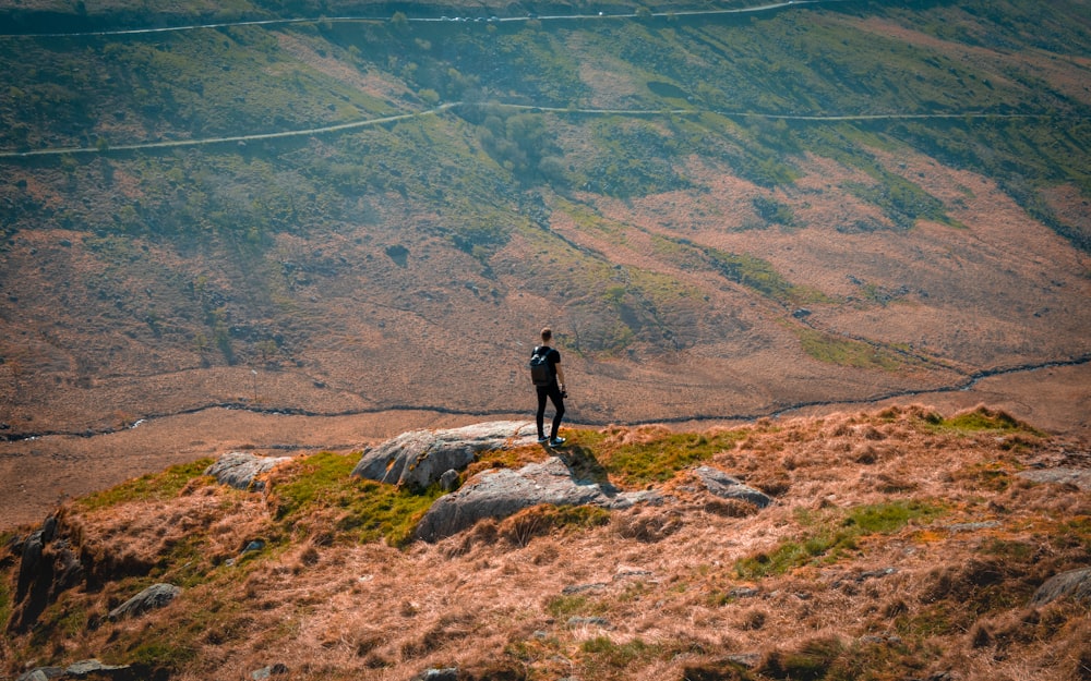 Un hombre parado en la cima de una exuberante ladera verde