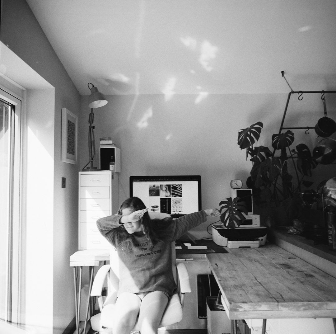 grayscale photo of woman sitting in front of desk