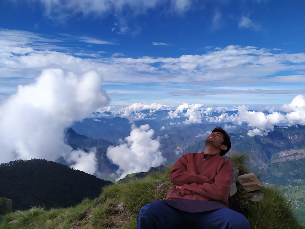 man in maroon long-sleeved shirt lying on mountain