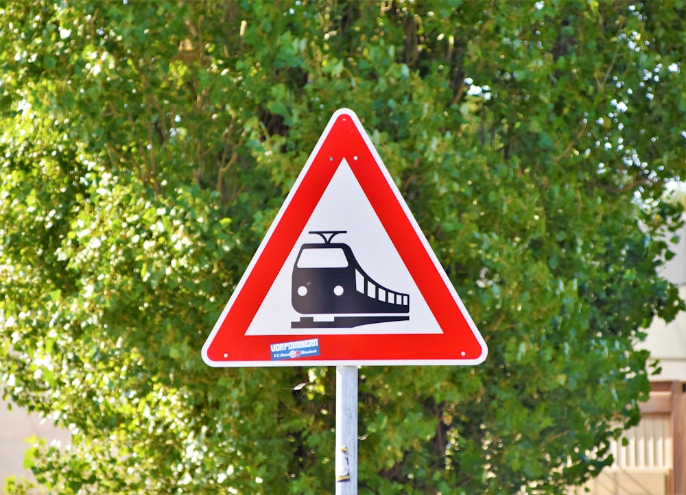 train road sign near green tree