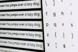 Various sizes of the sentence 'The quick brown fox jumps over a lazy dog' are printed in a typewriter-style font on the left, alongside a selection of letters and symbols in different styles on the right. The image captures a comparison of different fonts or typefaces.