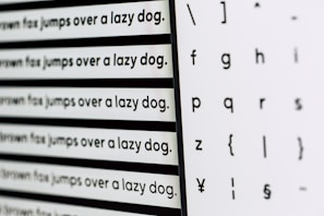 Various sizes of the sentence 'The quick brown fox jumps over a lazy dog' are printed in a typewriter-style font on the left, alongside a selection of letters and symbols in different styles on the right. The image captures a comparison of different fonts or typefaces.