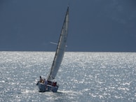 An elegant sailboat cutting through gentle waves under a bright blue sky.