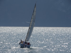 A sailboat cutting through sparkling blue water under a clear sky