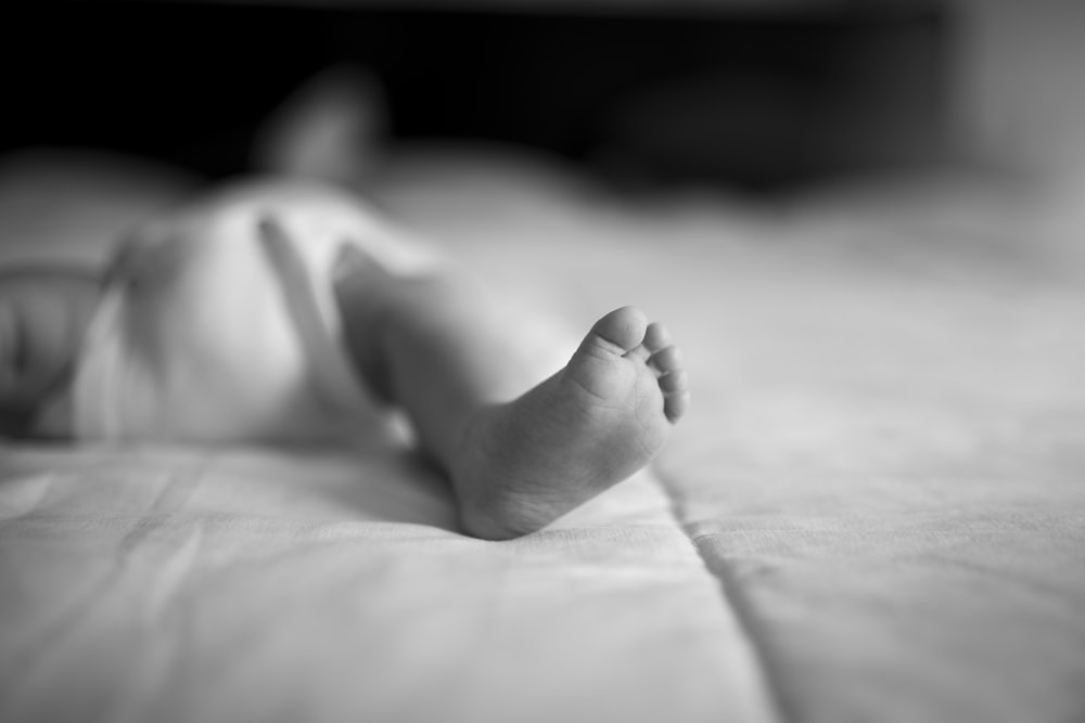grayscale photography of baby lying indoors
