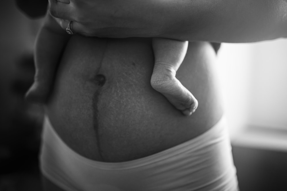 아기를 안고 있는 사람의 회색조 사진