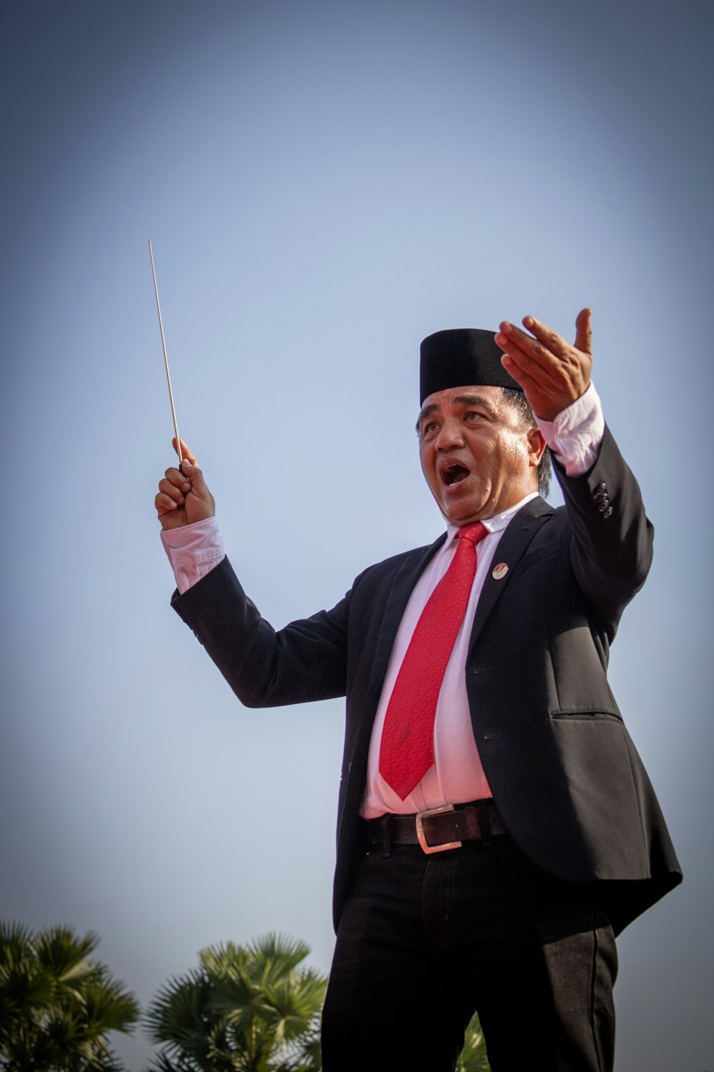 man wearing formal suit standing and beating using stick