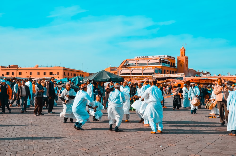 crowd of people walking near road beside buildings under blue and white sky during daytime