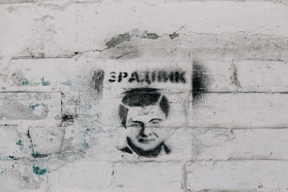 a graffiti of a man's face on a brick wall