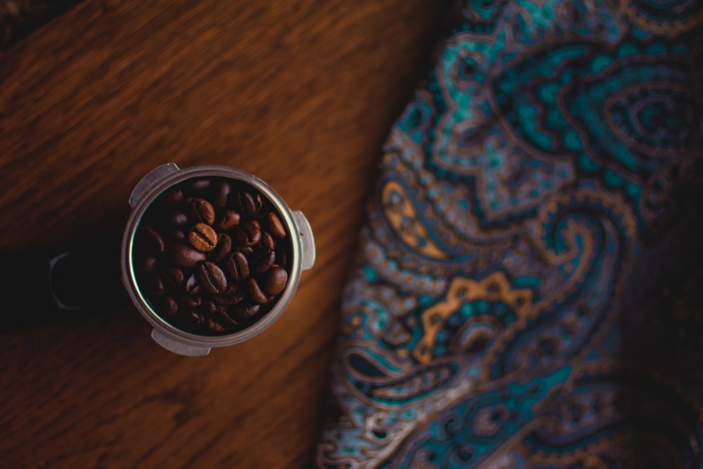 brown coffee beans in round gray stainless steel container