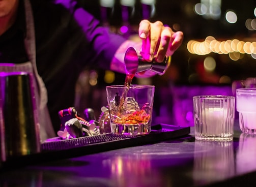 person pouring liquor in clear drinking glass