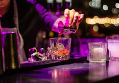 person pouring liquor in clear drinking glass