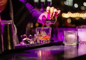 person pouring liquor in clear drinking glass