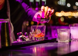 person pouring liquor in clear drinking glass