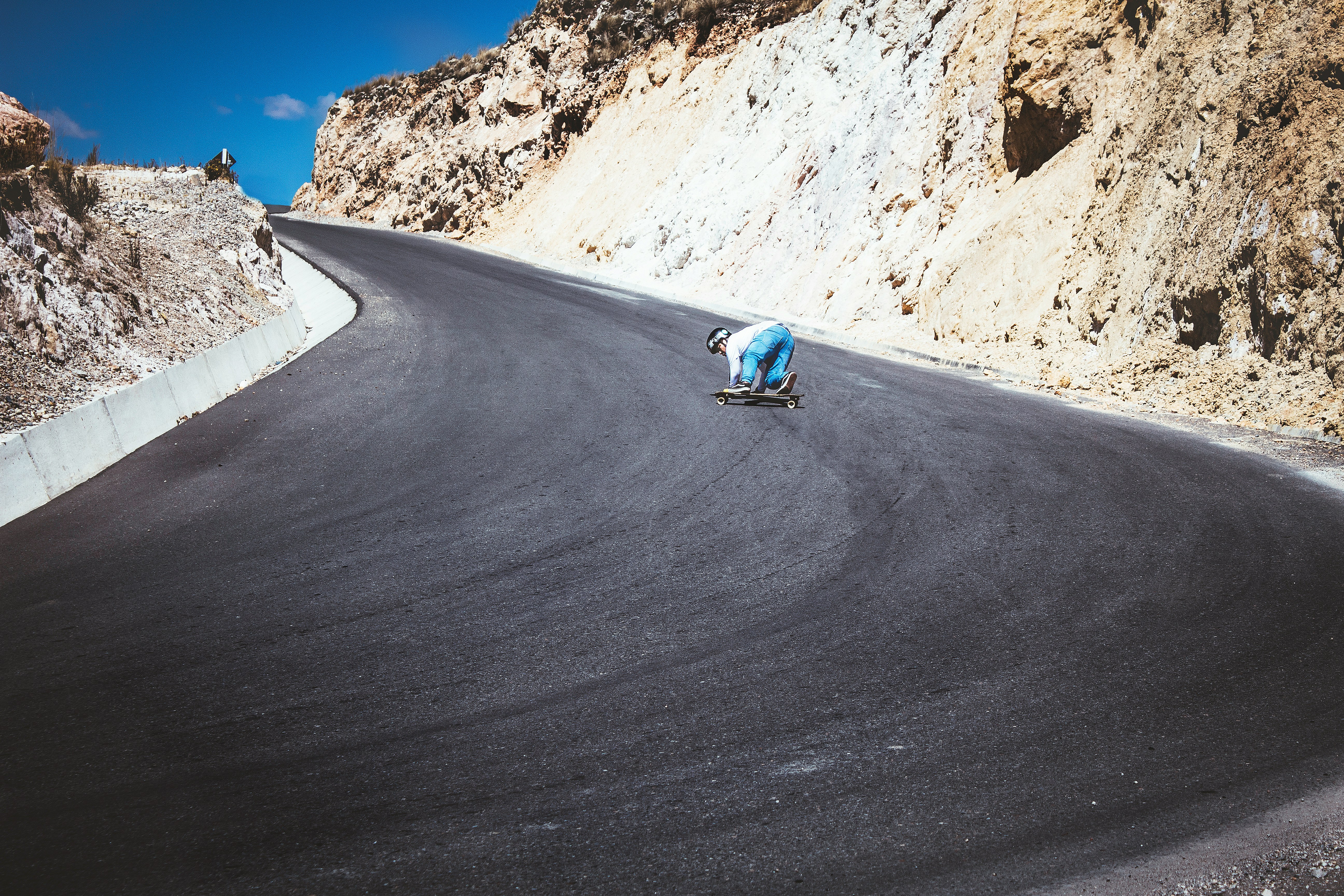 person riding board with wheels on road beside mountains