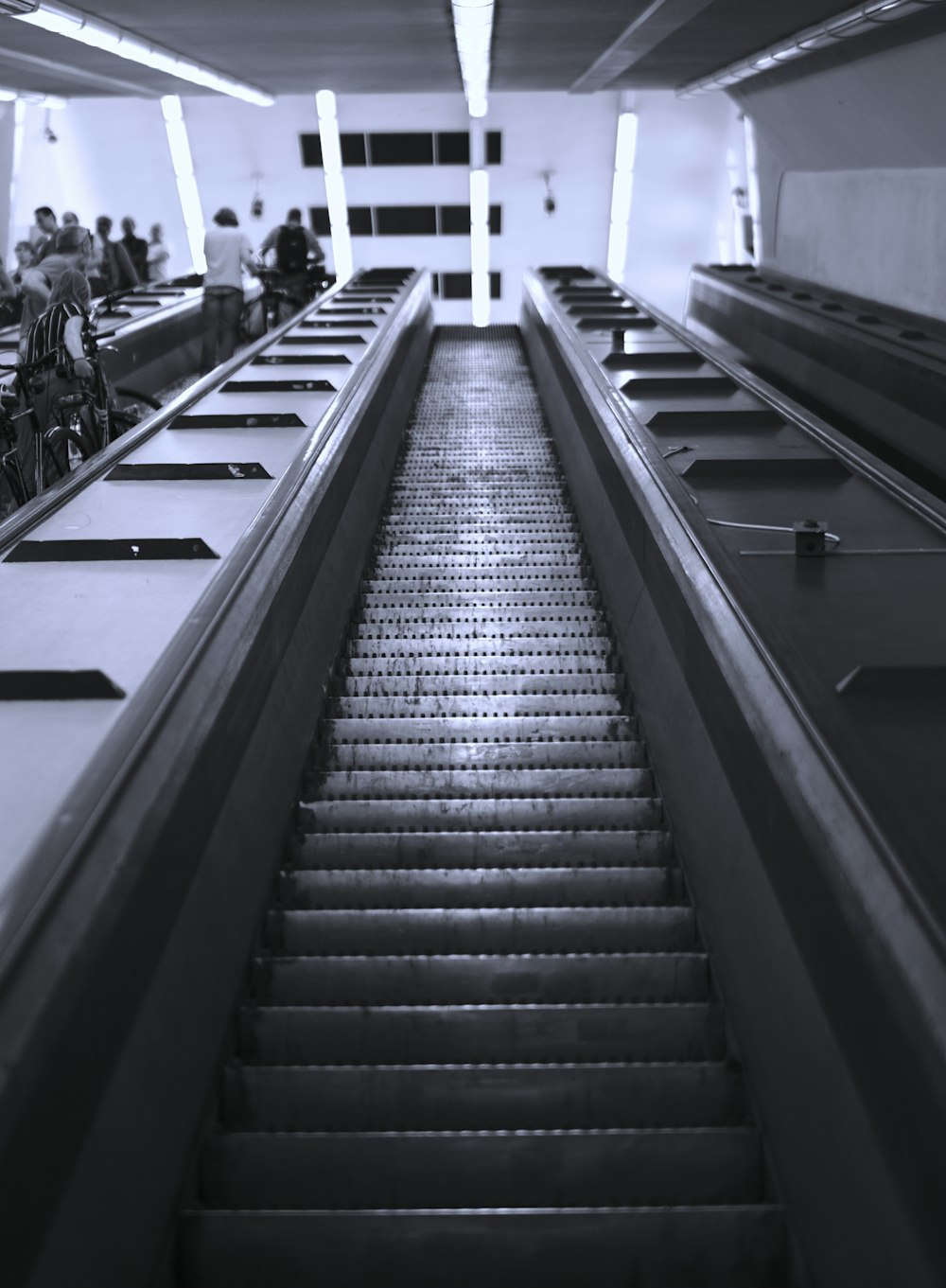 grayscale photography of people in escalator inside building