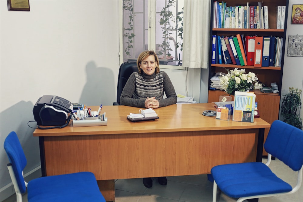 woman sitting beside desk near bookcase with books