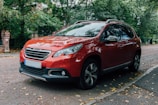 red Peugeot SUV parked beside curb