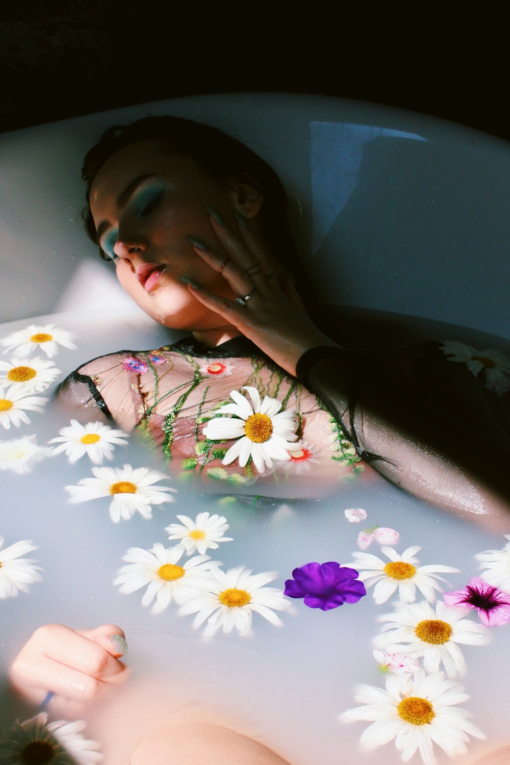 woman lying in bathtub with floating flowers
