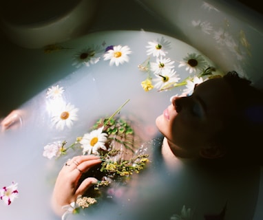 woman sitting in bathtub with white and yellow daisy flowers