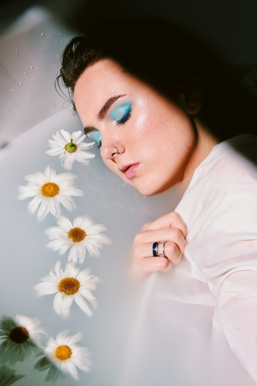 woman wearing white shirt near white and yellow daisy flowers