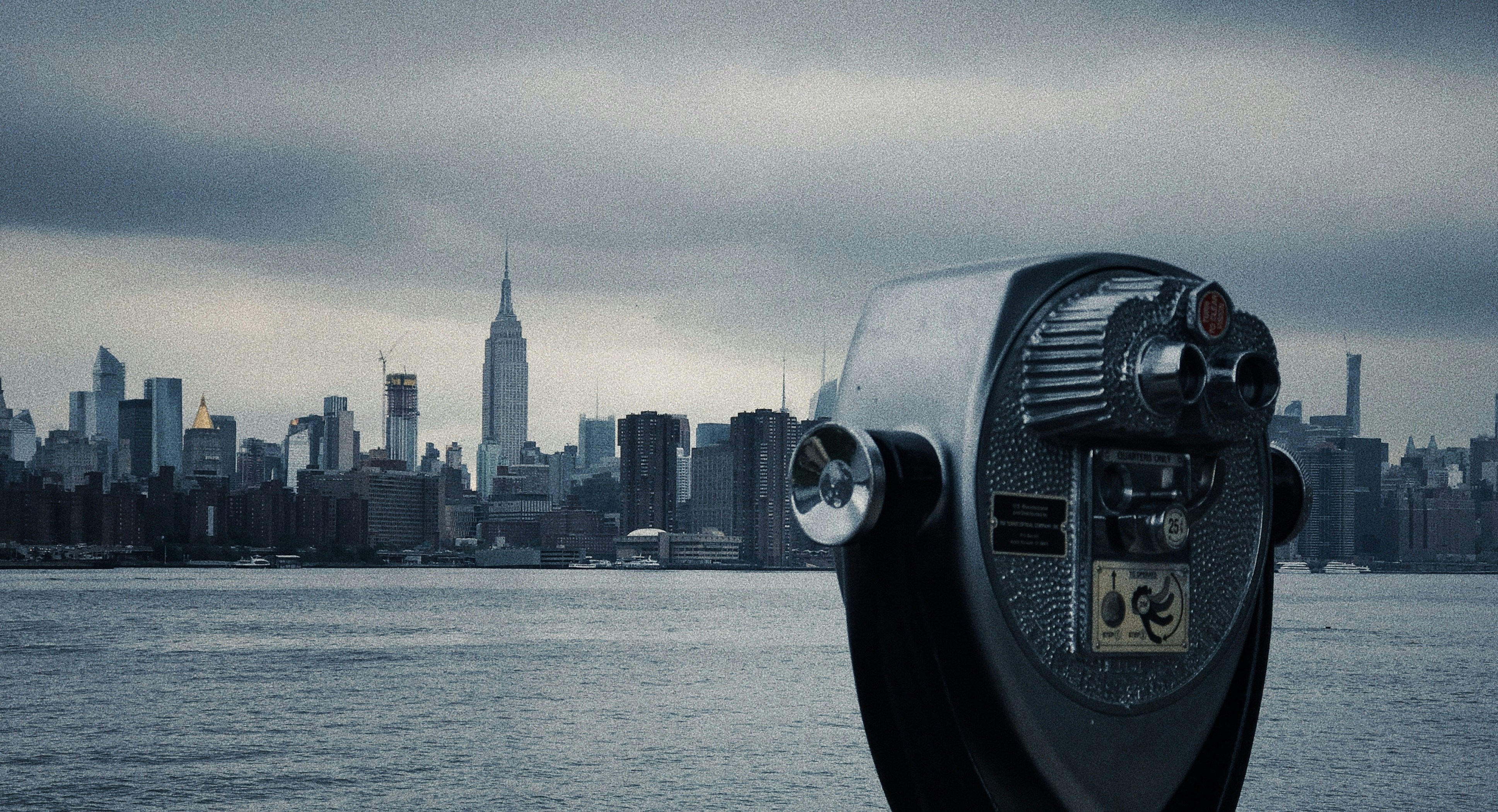 black and gray coin-operated telescope viewing sea and New York City under white and gray sky during daytime