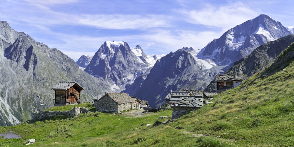 Häuser auf der grünen Wiese mit Blick auf den Berg unter blauem und weißem Himmel während des Tages