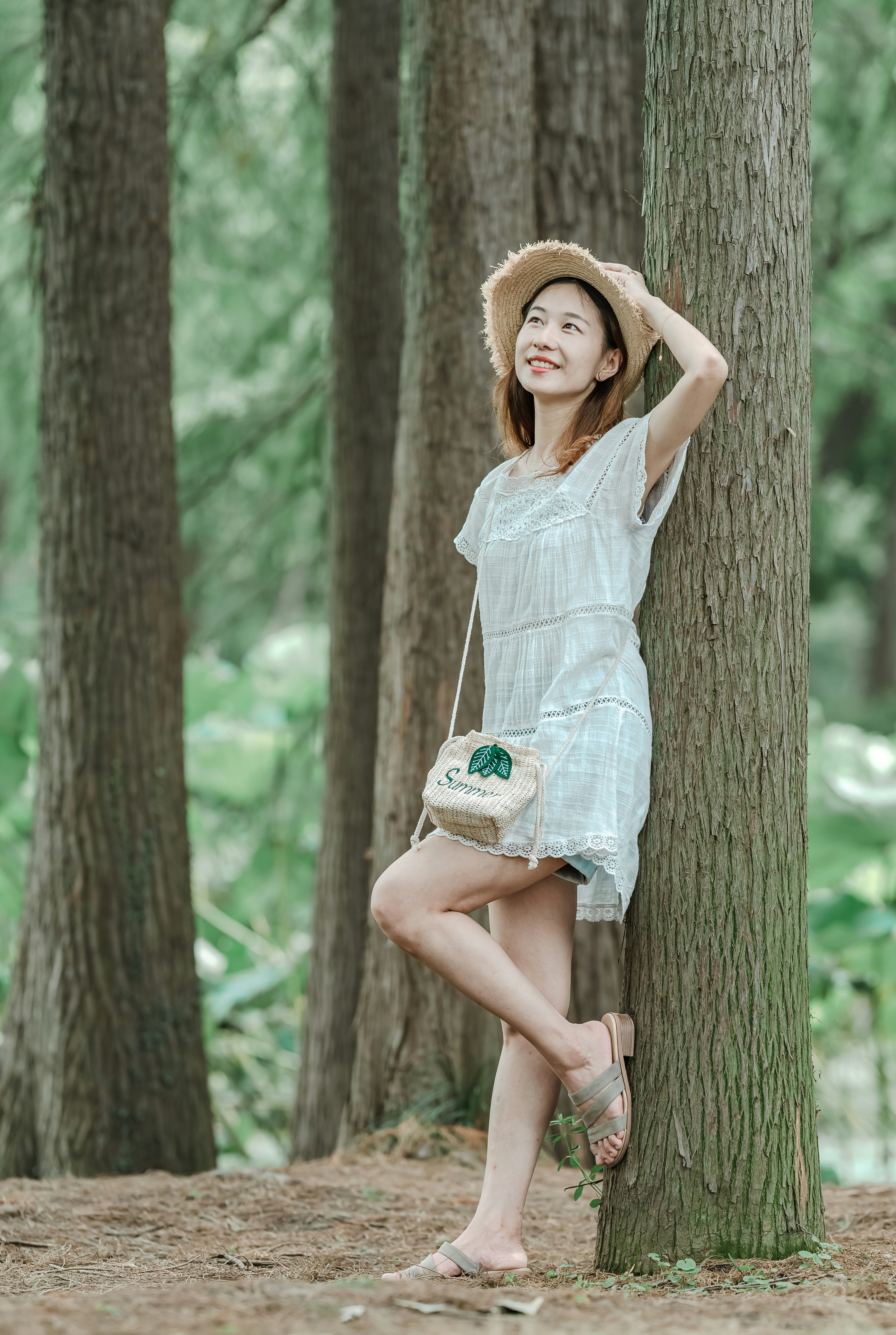 woman wearing gray cap-sleeved mini dress leaning on tree