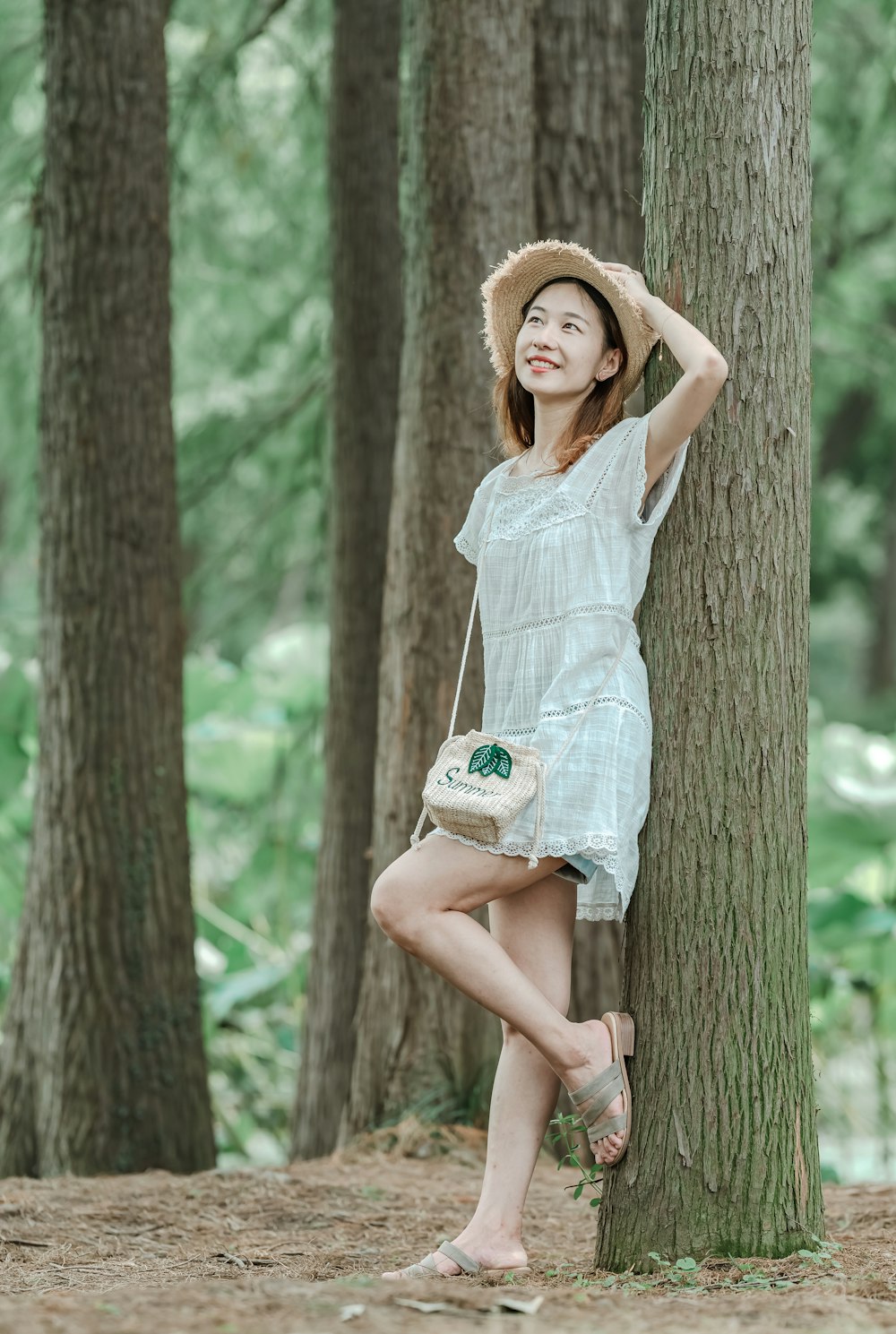 woman wearing gray cap-sleeved mini dress leaning on tree