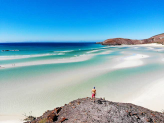 man standing on rock near sea