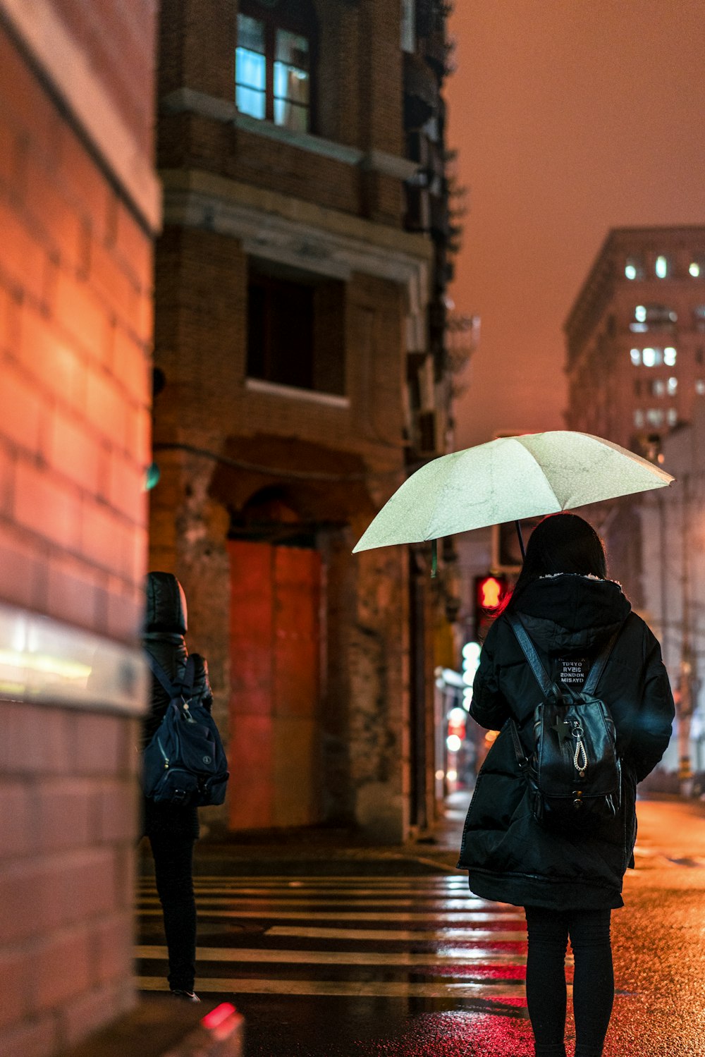 傘の下で歩道を歩く女性