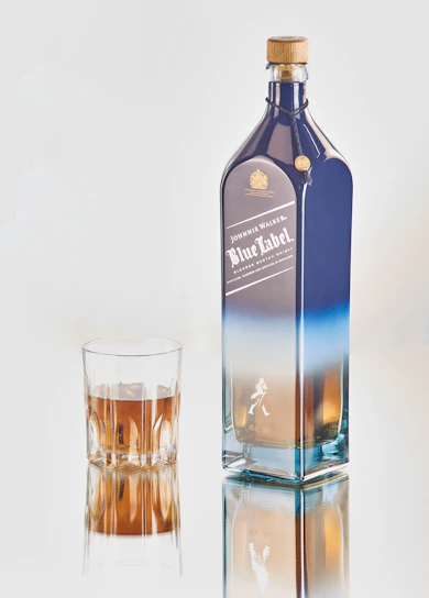 A sleek bottle of aged single malt whisky with a soft sky-blue background.